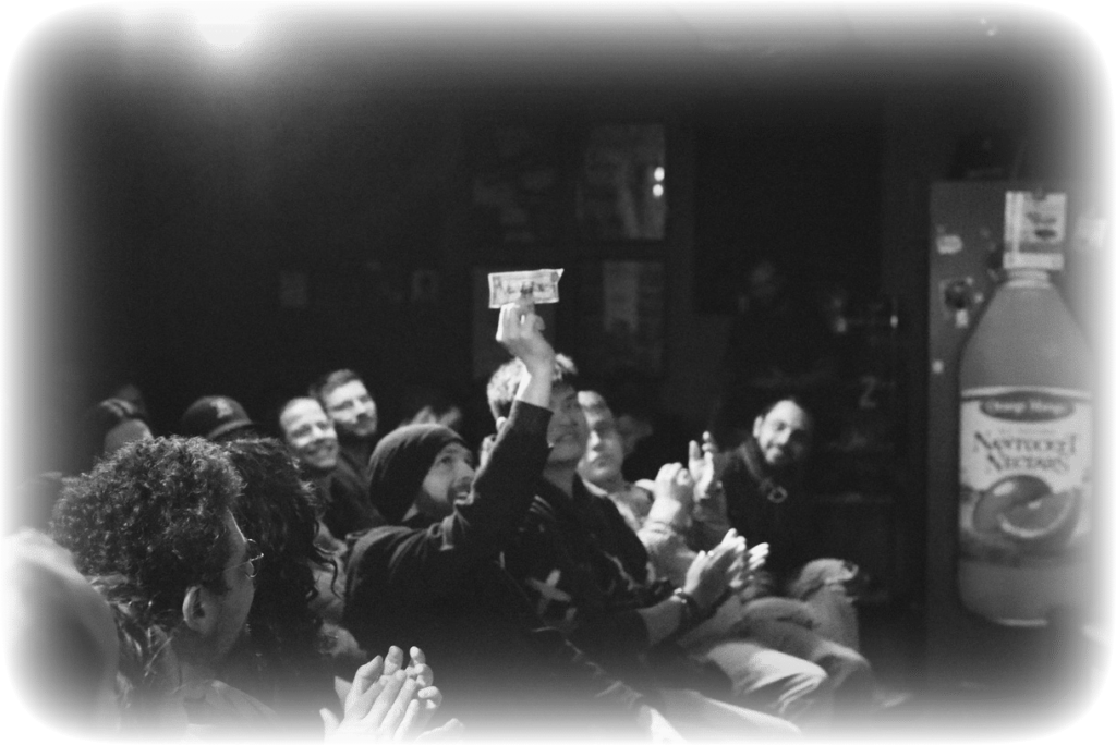 An audience member holding up a signed dollar bill during a performance by Eaden Marti.